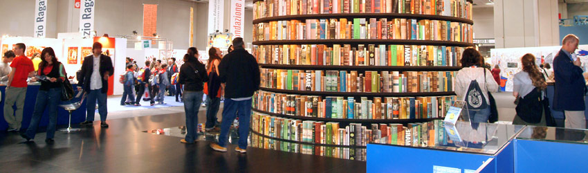 Le salon du livre : l’occasion de (re)découvrir le Petit Prince de Saint-Exupéry Photo d'une grande tour de livres au milieu d'une pièce